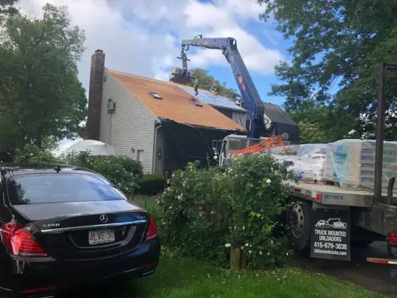 Roof tear-off with a delivery truck and crane