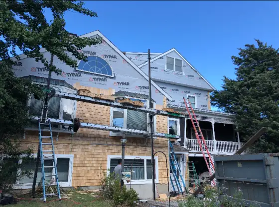 Siding replacement in progress with new cedar shakes
